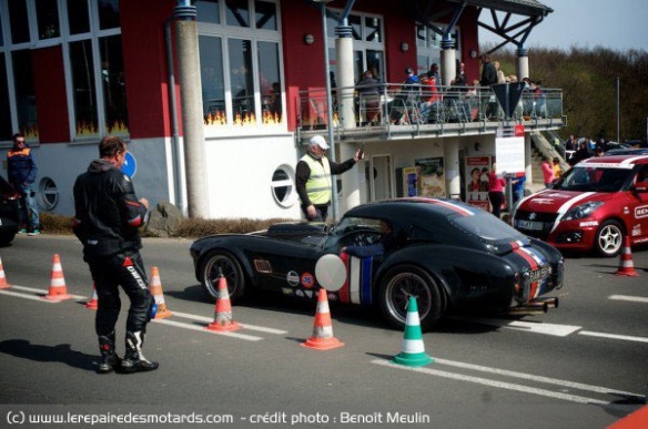 Nürburgring, un motard regarde passer une AC Cobra